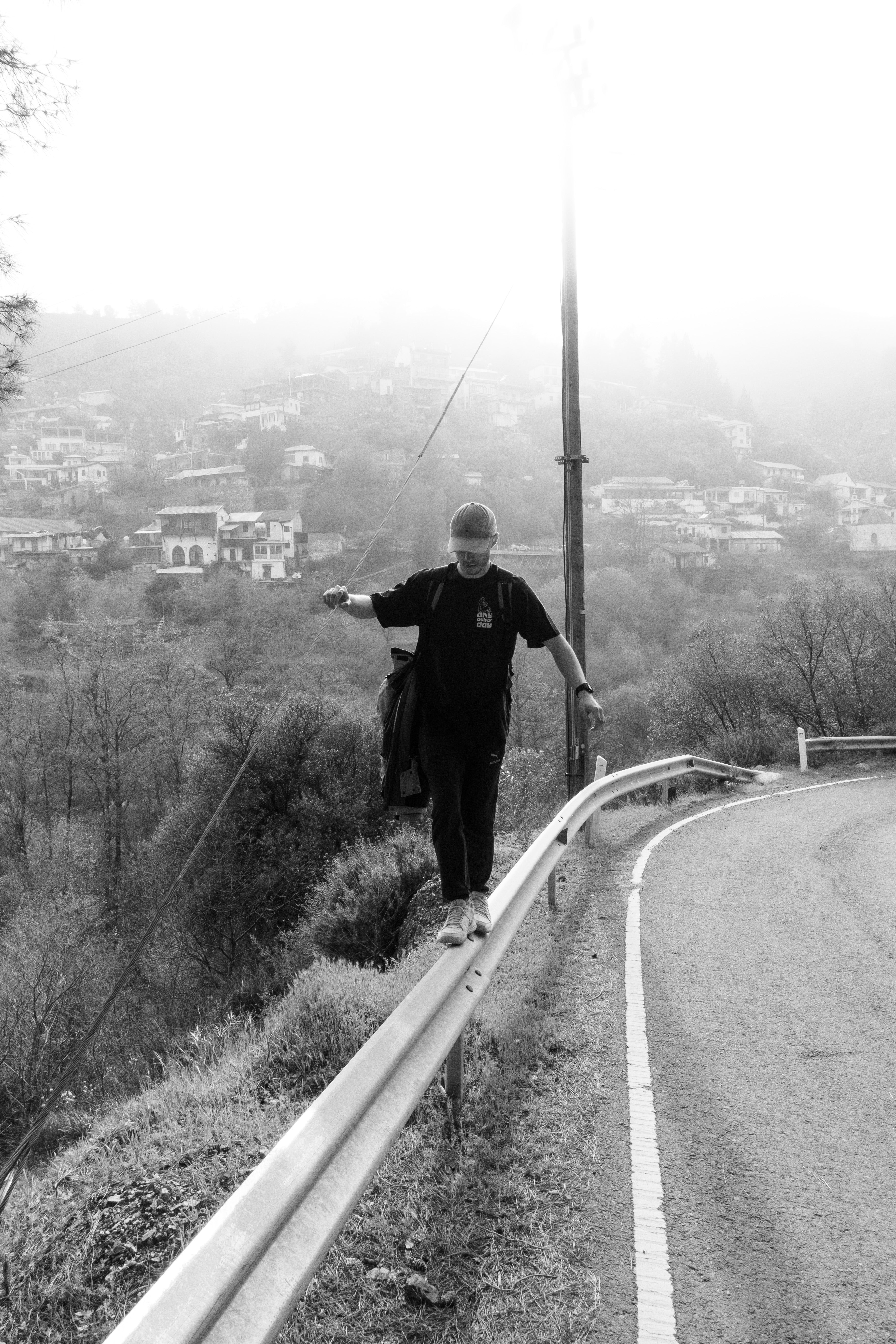 man balancing on the parapet with black t-shirt and powerful sun shining from behind